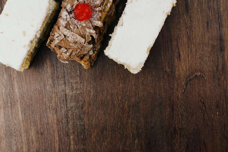 Puff pastry cakes with powdered sugar and cream and another with chocolate and a cherry on top on...