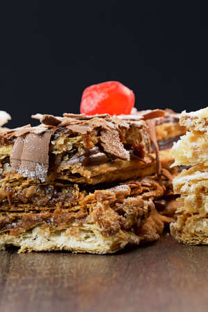 Puff pastry cakes with powdered sugar and cream and another with chocolate and a cherry on top on...