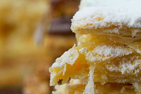 Puff pastry cakes with powdered sugar and cream and another with chocolate and a cherry on top on...