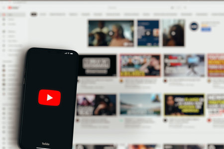 Youtube app on smartphone screen with website behind blurred. Global video player and streaming. Rio de Janeiro, RJ, Brazil. May 2021.のeditorial素材
