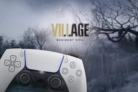 Playstation 5 Dual Sense controller with Resident Evil Village game blurred in the background. Rio...