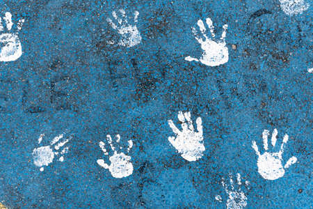 Drawing of children's hands painted on the asphalt in blue and white colors. Alphast texture and paint colors.の写真素材