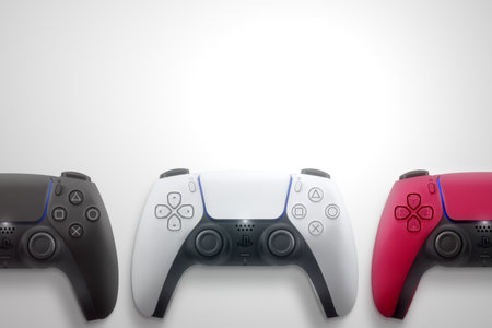 3 Playstation 5 Dual Sense controllers on white background. White, Cosmic Red and Midnight Black....