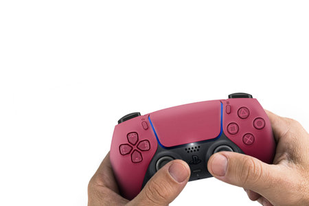 Male hand holding a Playstation 5 Dual Sense Cosmic Red Controller isolated on white background. Rio...