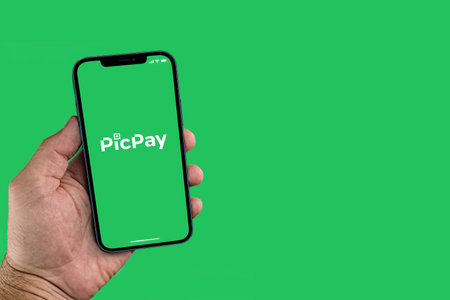 Male hand holding a smartphone with PicPay App on the screen. Green background. Rio de Janeiro, RJ, Brazil. July 2021.のeditorial素材