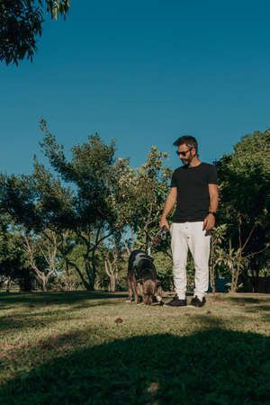 Brazilian guy with his pit bull dog in the public park. Affection and love relationship between...