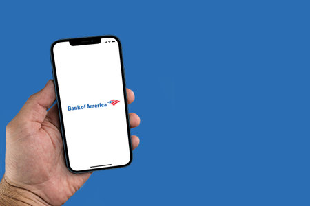 Male hand holding a smartphone with Bank of America app on screen. Blue background. Rio de Janeiro, RJ, Brazil. July 2021.のeditorial素材