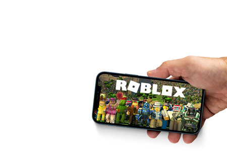 Male hand holding a smartphone with Roblox game app on the smartphone screen on white background. Rio de Janeiro, RJ, Brazil. August 2021.のeditorial素材