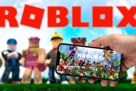 Male hand holding a smartphone with Roblox game app on the smartphone screen with the game blurred in the background. Rio de Janeiro, RJ, Brazil. August 2021.のeditorial素材
