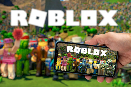 Male hand holding a smartphone with Roblox game app on the smartphone screen with the game blurred in the background. Rio de Janeiro, RJ, Brazil. August 2021.のeditorial素材
