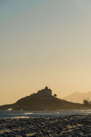 Sunset at Saquarema Beach in Rio de Janeiro, Brazil. Famous for waves and surfing. Church on top of...