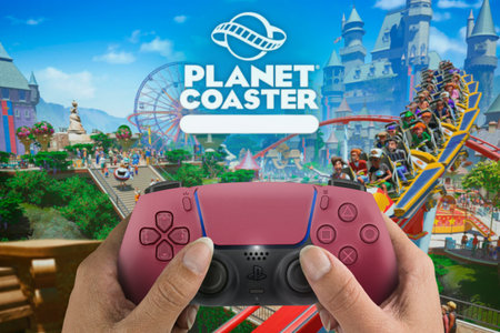 Female hand holding a Playstation 5 Dual Sense Controller with Planet Coaster game blurred in the...