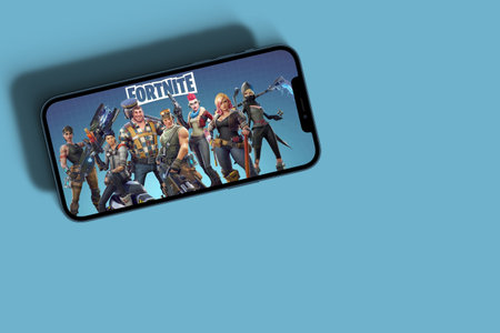 Fortnite mobile game app on smartphone screen with large shadow marked giving the feeling that you are taller on blue background. Rio de Janeiro, RJ, Brazil. September 2021.のeditorial素材