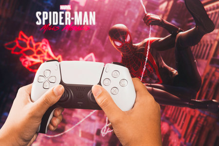 Female hand holding a Playstation 5 Dual Sense Controller with Marvel Spider-Man: Miles Morales game blurred in the background. Rio de Janeiro, RJ, Brazil. September 2021.のeditorial素材