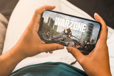 Female hand holding a smartphone with Call of Duty mobile game app on the screen. Rio de Janeiro,...