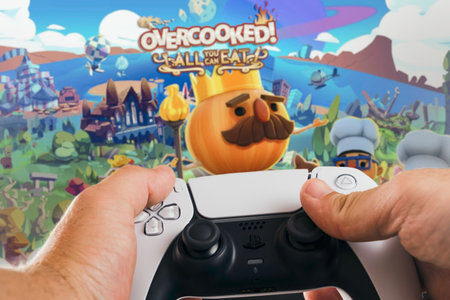 Male hand holding a Playstation 5 Dual Sense Controller with Overcooked, All you can eat, game...