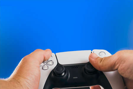 Man holding a Next generation white game controller isolated on blue background. Chroma Key.