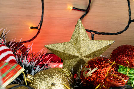 Wooden table with Christmas decorations. Red, silver and gold balls, gift boxes, lights, panettone, Christmas tree and others. Selective focus.の写真素材