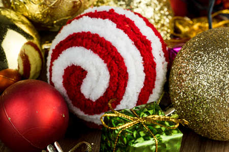 Wooden table with Christmas decorations. Red, silver and gold balls, gift boxes, lights, panettone, Christmas tree and others. Selective focus.の写真素材