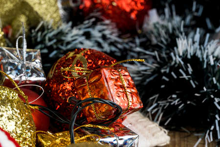 Wooden table with Christmas decorations. Red, silver and gold balls, gift boxes, lights, panettone, Christmas tree and others. Selective focus.の写真素材