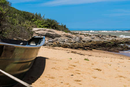 View of the Joana beach in Rio das Ostras in Rio de Janeiro. Sunny day, blue sky. Strong sea and yellowish sand and lots of rocks.の写真素材