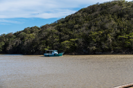 View of the beach of Rio das Ostras with the meeting of the river in Rio de Janeiro. Sunny day, blue sky. Yellow sand and some rocks. Wooden bridge to cross. Boats and fishing on the pier.の写真素材