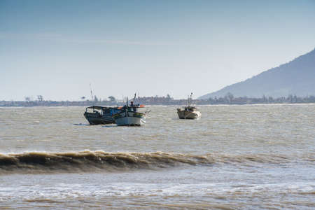 View of the beach of Rio das Ostras with the meeting of the river in Rio de Janeiro. Sunny day, blue sky. Yellow sand and some rocks. Wooden bridge to cross. Boats and fishing on the pier.の写真素材