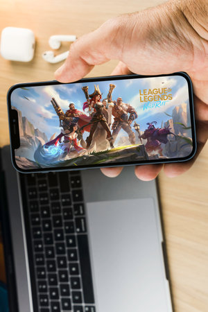 Male hand holding a smartphone with League of Legends (LOL) mobile game app on the screen with a...