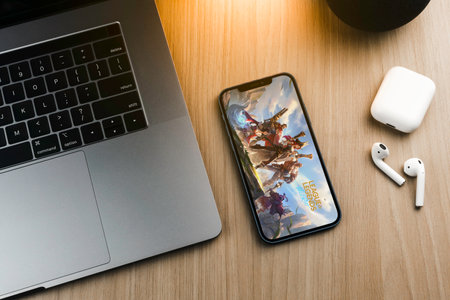 League of Legends (LOL) mobile game app on the smartphone screen on wooden background with a computer beside it. Rio de Janeiro, RJ, Brazil. September 2021.のeditorial素材