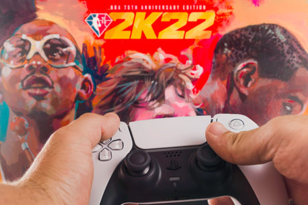 Male hand holding a Playstation 5 Dual Sense Controller with NBA 2k22 Basketball game blurred in the background. Rio de Janeiro, RJ, Brazil. October 2021.のeditorial素材
