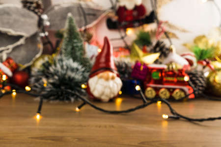 Wooden table with Christmas decorations. Red, silver and gold balls, gift boxes, lights, Santa Claus, Panettone, Christmas tree and others. Selective focus.の写真素材