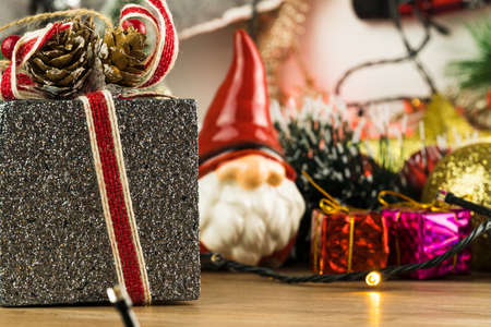 Wooden table with Christmas decorations. Red, silver and gold balls, gift boxes, lights, Santa Claus, Panettone, Christmas tree and others. Selective focus.の写真素材