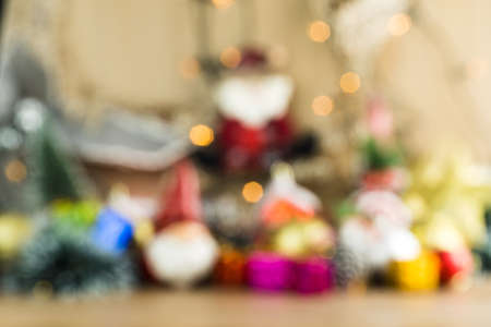 Blurred wooden table background with Christmas baubles. Red, silver and gold balls, gift boxes, lights, panettone, Christmas tree and others to insert something in front in focus.の写真素材