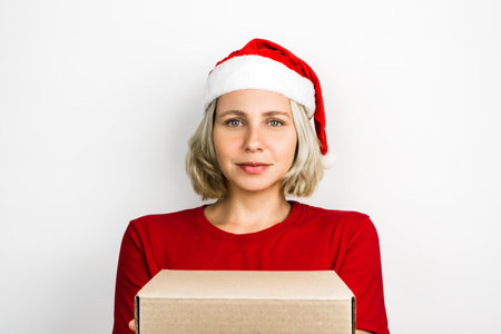 Young beautiful girl with Santa Claus accessories such as Santa's Cap and red outfit isolated on white background. Photo for Christmas. Brazilian, Caucasian, blonde hair, green eyes.の写真素材