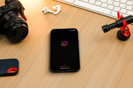 Instagram app on smartphone iPhone 13 Pro screen on wooden table. Content creator environment with...
