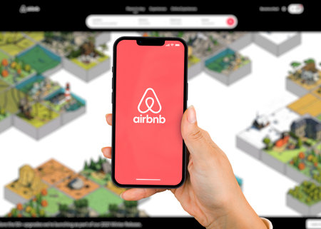 Female hand holding a smartphone iPhone 13 Pro with Airbnb app on the screen. Website blurred in the background. Rio de Janeiro, RJ, Brazil. November 2021.のeditorial素材