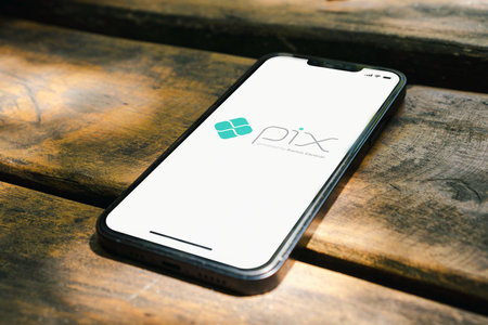 Pix app (instant payment system from Central Bank of Brazil) on the smartphone screen on the rustic wooden table in the park. Top view. Rio de Janeiro, RJ, Brazil. January 2022.のeditorial素材