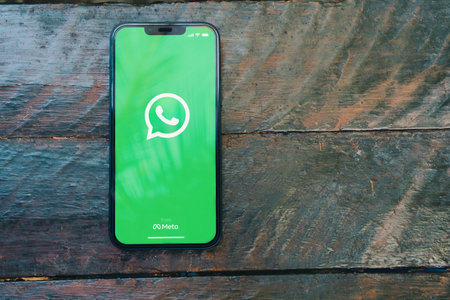 WhatsApp app on the smartphone screen on the rustic wooden table in the park. Top view. Rio de Janeiro, RJ, Brazil. January 2022.のeditorial素材