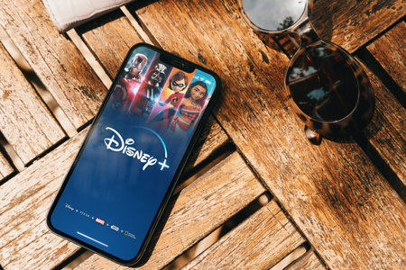 Disney+ (Disney Plus) app on the smartphone screen on the wooden table. Top view. Rio de Janeiro, RJ, Brazil. March 2022.のeditorial素材