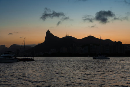 Sunset in the bay of Guanabara, cove and beaches of Rio de Janeiro, Brazil with its buildings, boats and landscape. Christ the Redeemer on top of Corcovado. Reflection of the sky in the sea.の写真素材