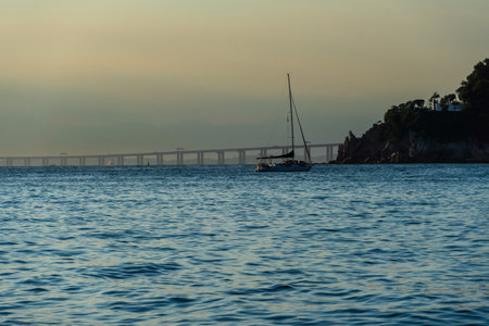 Sailing boat in Guanabara Bay in Rio de Janeiro, Brazil with a hill in the background. Beautiful landscape with the sea at sunset. Sailing boats and speedboats in the bay.の写真素材