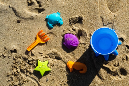 Colorful children's toys to play in the sand at the beach or pool. Children's shovel, bucket and molds for the sandbox under the sea. Sunny day.の写真素材