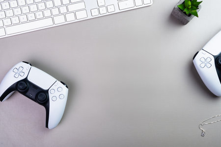 Gray office desk with Next Generation white game controller around the edges and keyboard. Space for textの写真素材