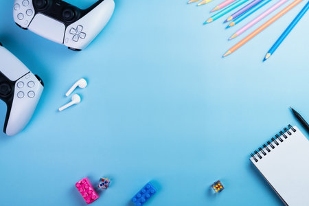 Blue children's table with Next Generation white game controller, colored pencils, earphone and dice. Child accessories. Kids. Space for text. and say. Child accessories. Kids. Space for text.の写真素材
