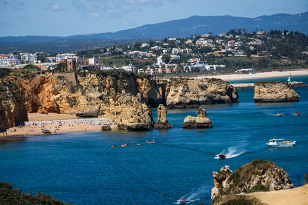 Ponta da Piedade near Lagos in Algarve, Portugal. Cliff rocks and tourist boat on sea. Dona Ana Beach, Students beach. Sunny day. Point of Pity.の写真素材