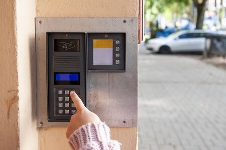 Hand pushing key of the modern digital intercom with numeric keypad and passcard sensor