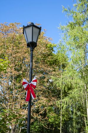 Bow in colors of polish national flag tied on the street lamp. Concept of patriotism.の写真素材