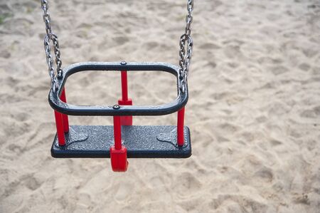Closeup of empty swings at the playground. Foggy autumn morning in the cityの写真素材