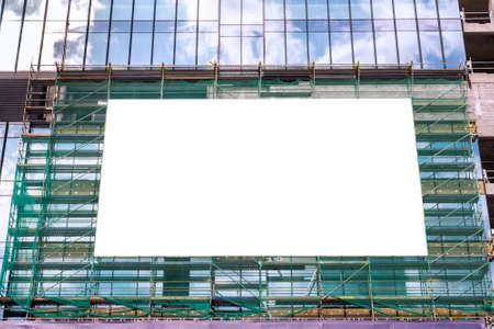 Blank white billboard for advertisement on the scaffolding. Modern office building under cosntructionの写真素材