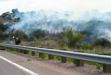 RURAL ARIZONA NEAR TUCSON - JULY 11 2009: Fireman fighting a wildfire at the roadside. The background is full of smoke.のeditorial素材